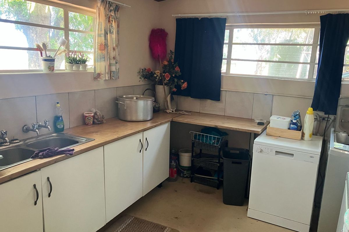 A functional kitchen area featuring a stainless steel sink, laminate countertops, and tiled backsplash, offering a practical layout for food preparation and utility tasks.