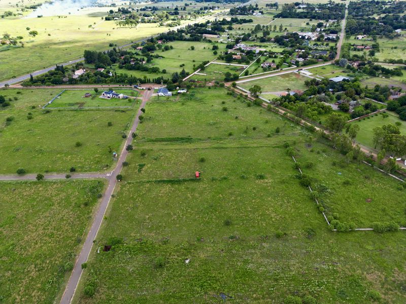 An aerial view of a large, undeveloped residential plot featuring established access roads and surrounding rural landscape.