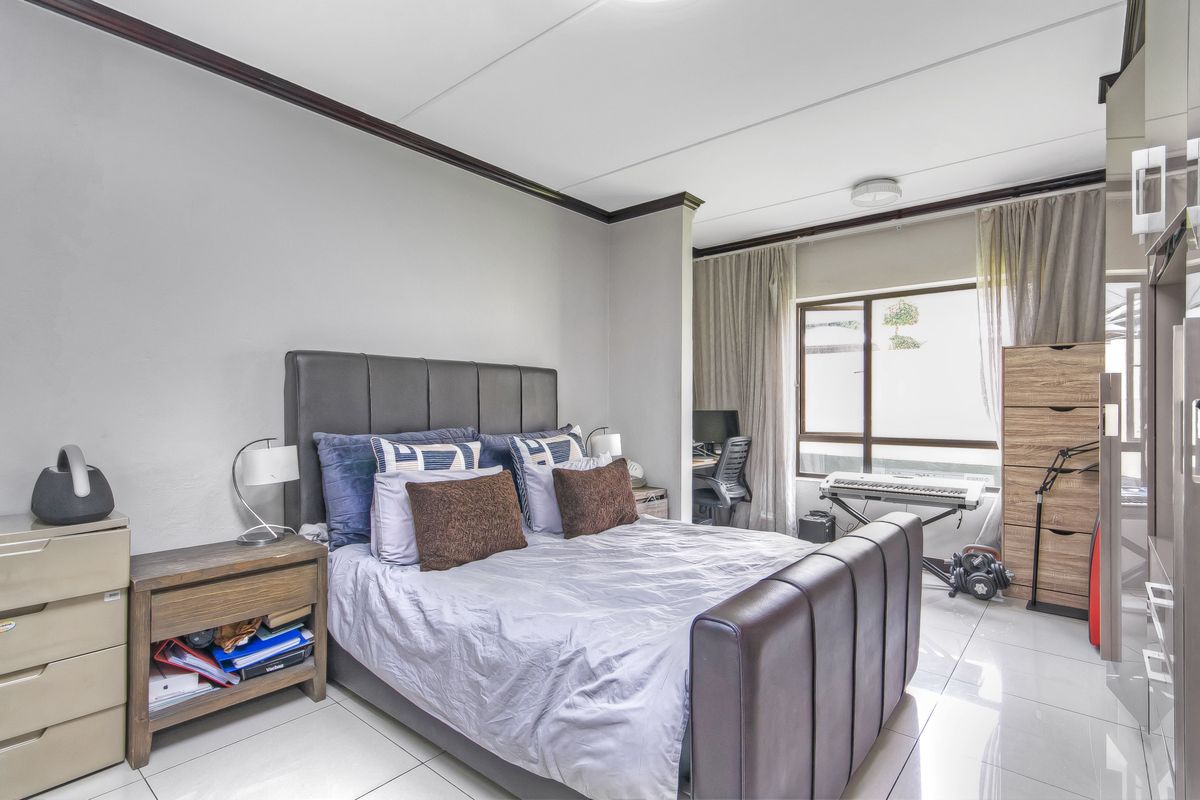 A bedroom featuring tiled flooring, crown molding, and a large window providing natural light, with an integrated study nook area.