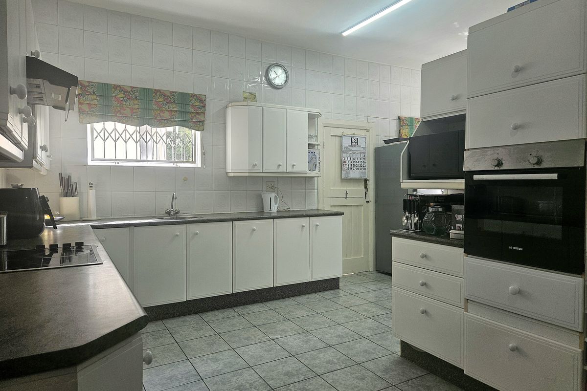A functional kitchen featuring white built-in cabinetry, laminate countertops, a built-in oven, and tiled finishes throughout.
