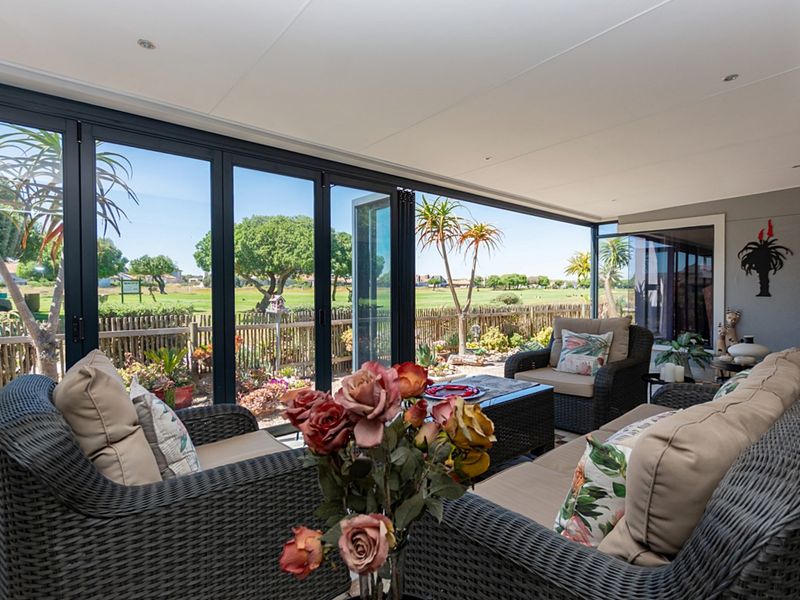 A bright, enclosed patio featuring large bi-fold glass doors that provide seamless indoor-outdoor flow and expansive views of the surrounding garden and landscape.