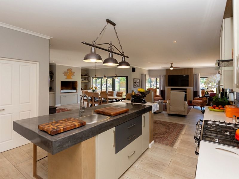 Spacious open-plan living area featuring a modern kitchen with a central island, gas hob, and seamless flow into the dining and lounge spaces.