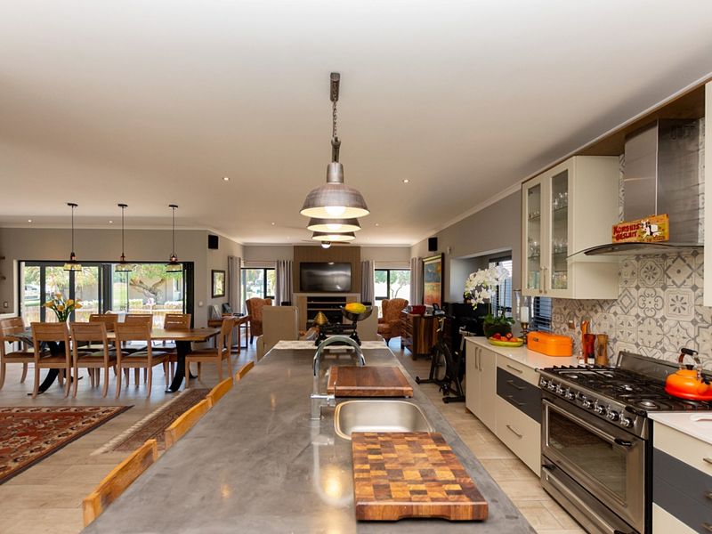 Spacious open-plan living area featuring a modern kitchen with a large island, stainless steel gas range, and seamless flow to the dining and lounge spaces.