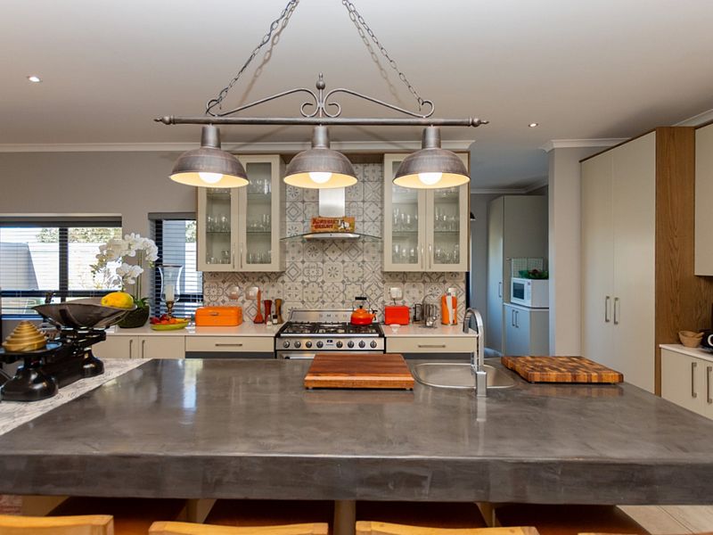 Modern kitchen featuring a large concrete island, gas stove with extractor fan, patterned tile backsplash, and ample built-in cabinetry.