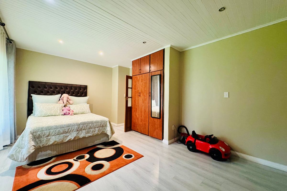 Spacious bedroom featuring light-toned laminate flooring, a white tongue-and-groove ceiling with recessed lighting, and built-in wooden cabinetry.