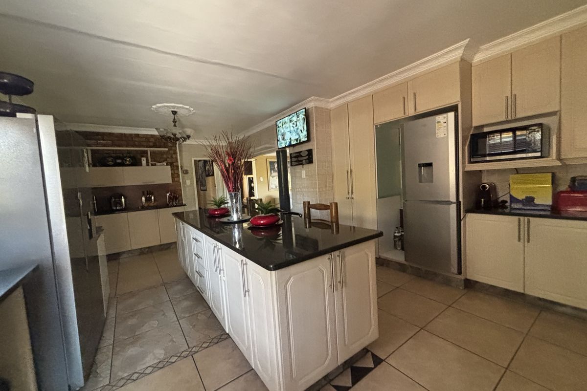 Spacious kitchen featuring a central island with granite countertops, ample built-in cabinetry, and tiled flooring throughout.