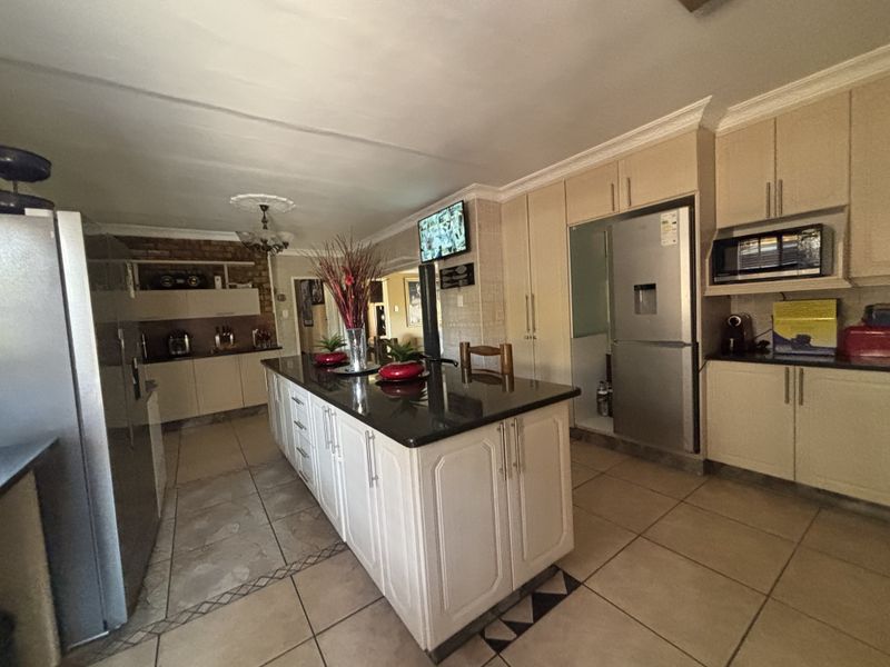 Spacious kitchen featuring a central island with granite countertops, ample built-in cabinetry, and tiled flooring throughout.