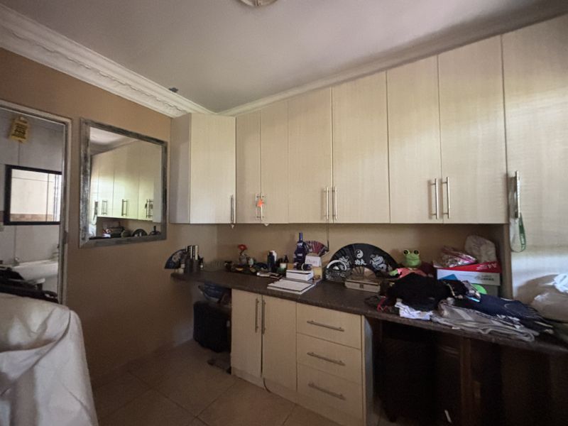 A functional scullery or utility area featuring built-in cabinetry, laminate countertops, and tiled flooring, offering practical storage space for household tasks.