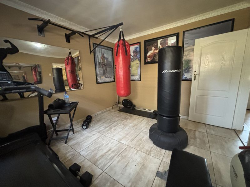 A dedicated home gym space featuring tiled flooring, wall-mounted fitness equipment brackets, and coving detail.