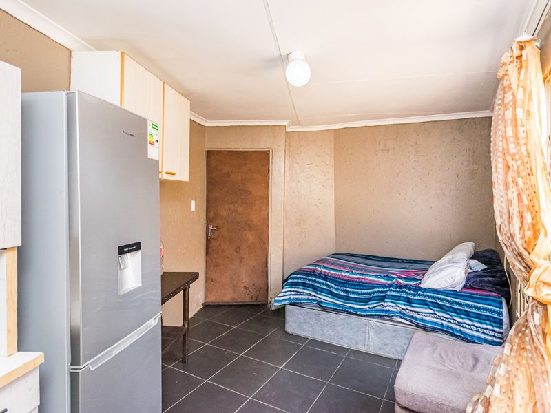 Compact open-plan living area featuring tiled flooring and basic built-in cabinetry, suitable for a studio-style layout.