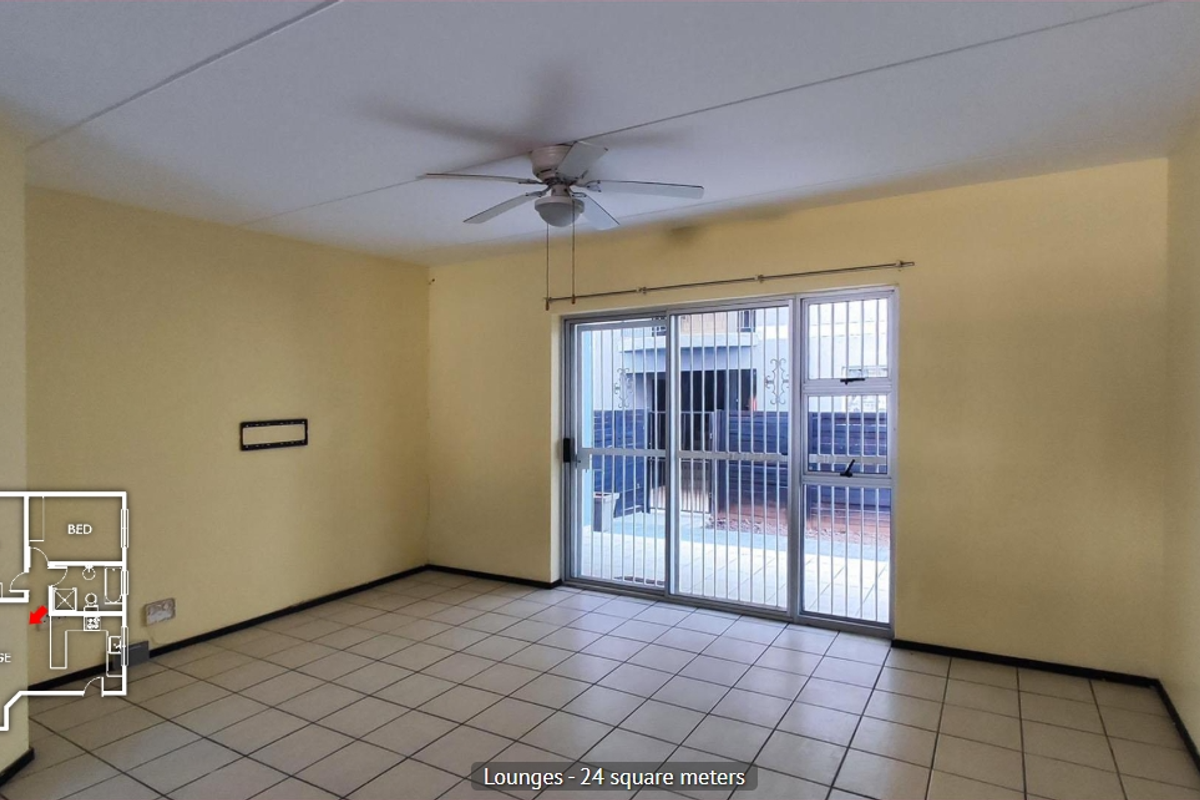 Spacious living area featuring tiled flooring, a ceiling fan, and large sliding glass doors providing access to the patio.