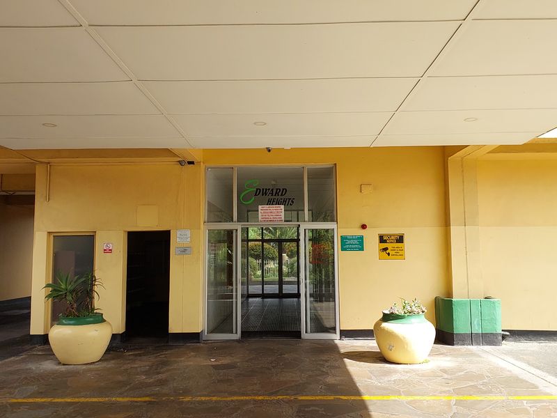 The main entrance to Edward Heights apartment complex, featuring a covered driveway approach, glass doors, and building signage.