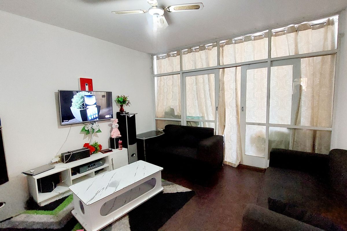 A living room featuring laminate flooring, a ceiling fan, and large glass sliding doors that provide natural light.