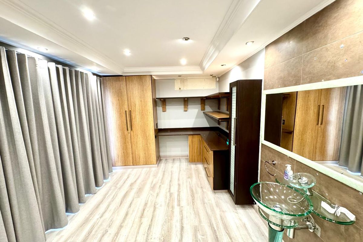 A multi-purpose room featuring built-in wooden cabinetry, a desk workspace, and a modern glass vessel sink vanity with tiled wall finish.