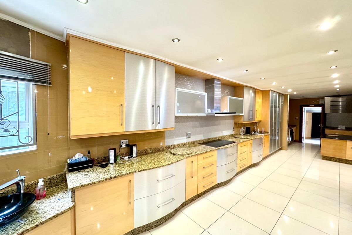 Spacious modern kitchen featuring granite countertops, light wood and metallic cabinetry, integrated hob, extractor fan, and polished floor tiles.