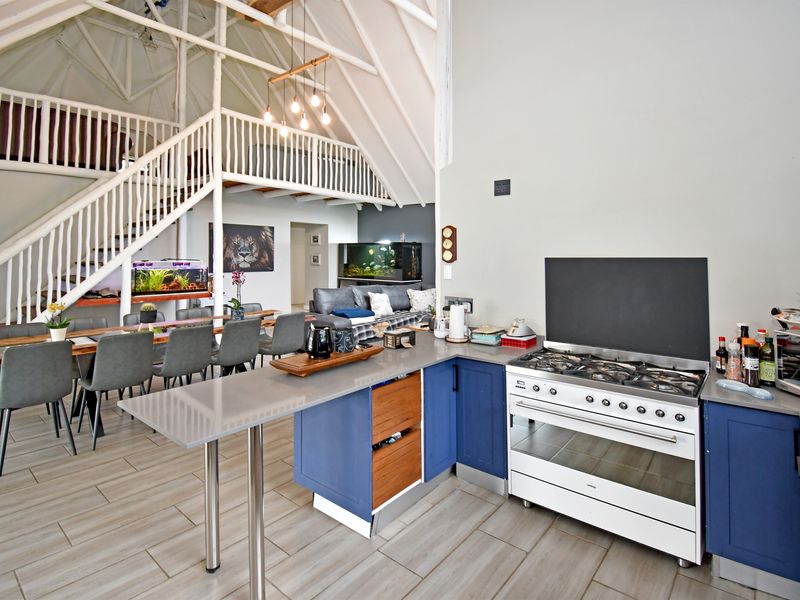 Spacious open-plan kitchen and living area featuring a gas stove, modern cabinetry, and a mezzanine level with exposed roof trusses.