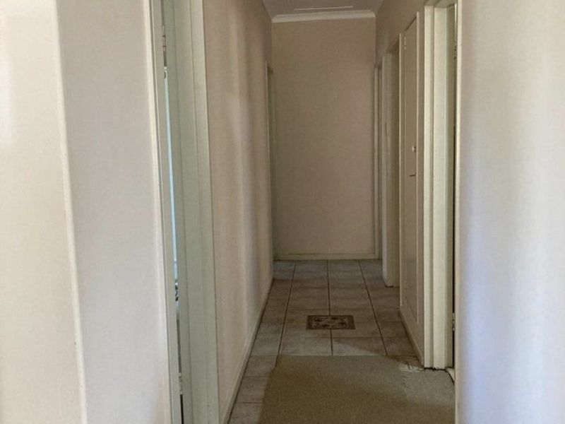 A functional hallway featuring neutral wall finishes and tiled flooring, providing access to multiple rooms within the home.