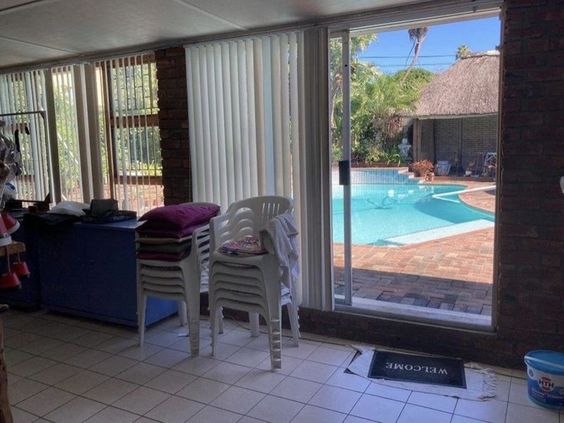 Enclosed patio area featuring exposed brick walls, tiled flooring, and sliding glass doors providing direct access to the outdoor pool area.