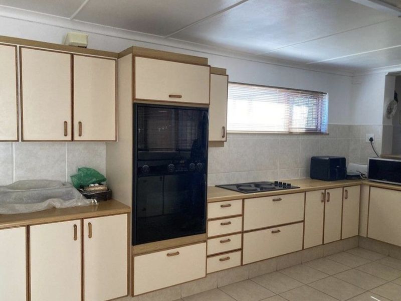 A functional kitchen featuring built-in oven, gas hob, tiled splashbacks, and ample laminate cabinetry with tiled flooring.