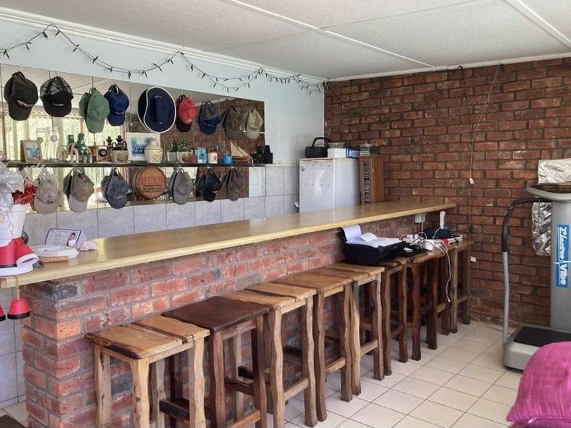 A rustic home bar area featuring an exposed brick counter, brick feature wall, and mirrored backsplash with integrated shelving.