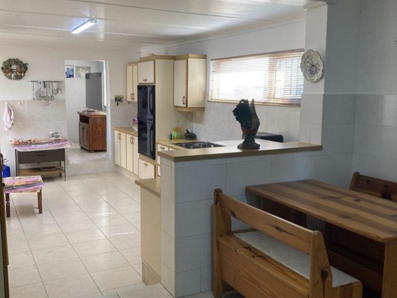 Open plan kitchen and dining area featuring tiled flooring, built-in cabinetry, and a tiled breakfast counter.