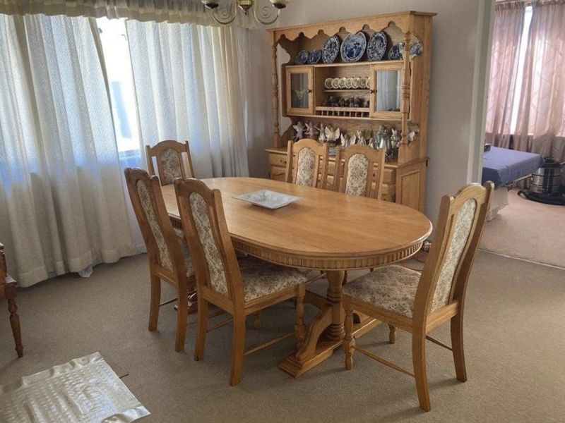 A traditional dining room featuring carpeted flooring and large windows with curtains, providing a functional space for family meals.