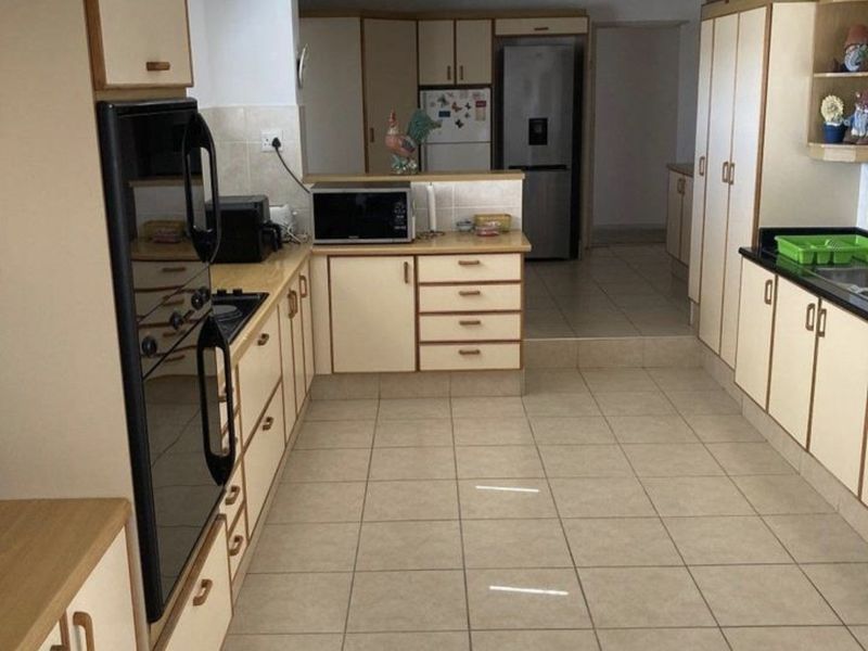 A functional kitchen featuring tiled flooring, built-in cabinetry, and integrated appliances, offering a practical layout with potential for modern cosmetic updates.