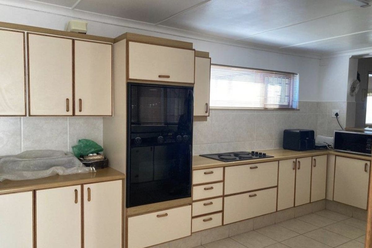 A functional kitchen featuring built-in oven, gas hob, tiled splashbacks, and ample laminate cabinetry with tiled flooring.