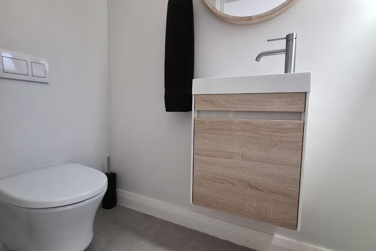 Modern guest bathroom featuring a wall-hung vanity with wood-look finish, basin, and a wall-hung toilet with a concealed cistern.