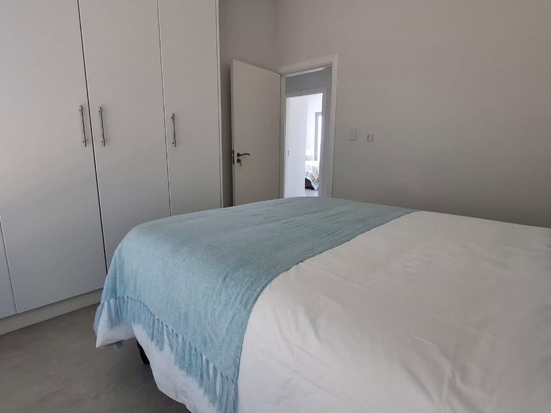 A clean and well-maintained bedroom featuring neutral tiled flooring and ample built-in cupboard storage.