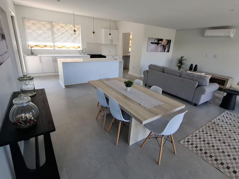 Spacious open-plan living area featuring a modern kitchen with a central island, tiled flooring, and integrated air conditioning, creating a bright and functional space.