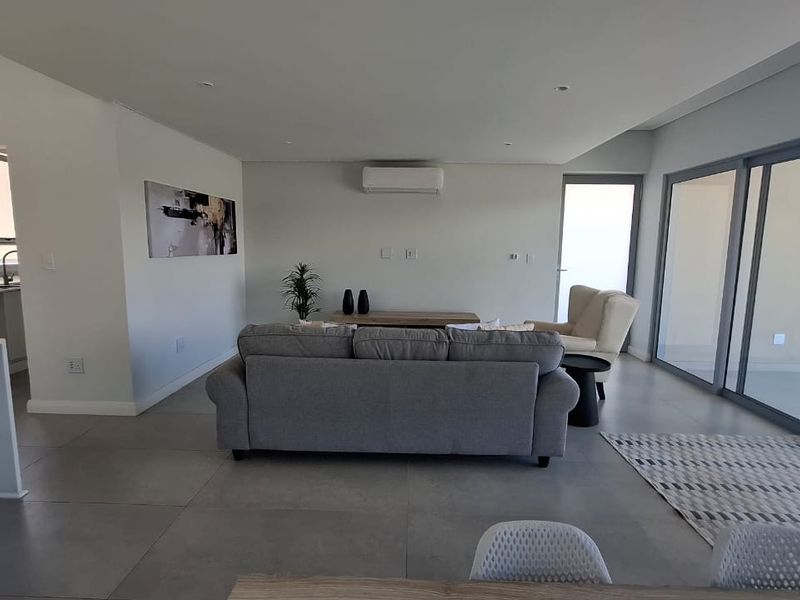 Spacious open-plan living area featuring large format floor tiles, recessed lighting, a split-system air conditioner, and seamless access to the outdoor space.