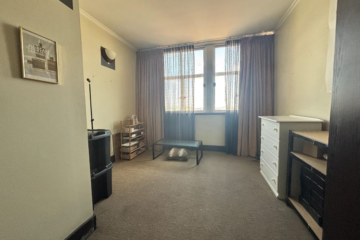 A bedroom featuring carpet flooring, coving, and large windows with curtains. The space requires cosmetic updates to improve its overall condition.