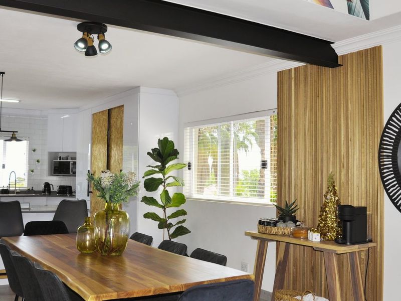 Modern open-plan living and dining area featuring a striking exposed steel beam, slatted timber feature wall, and a sleek, well-appointed kitchen.