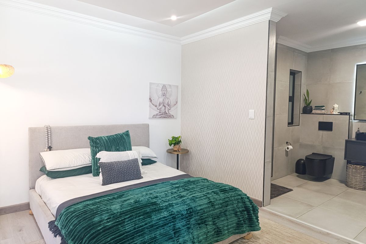 A modern bedroom featuring crown molding, recessed lighting, and an open-plan en-suite bathroom with contemporary tiling and a wall-mounted toilet.