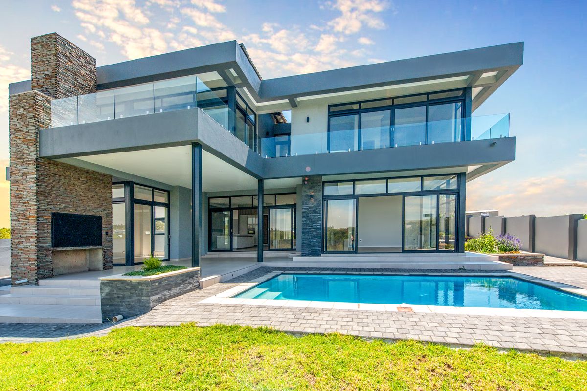 Modern double-story residence featuring a swimming pool, expansive glass sliding doors, stone-clad fireplace, and spacious covered patio area.