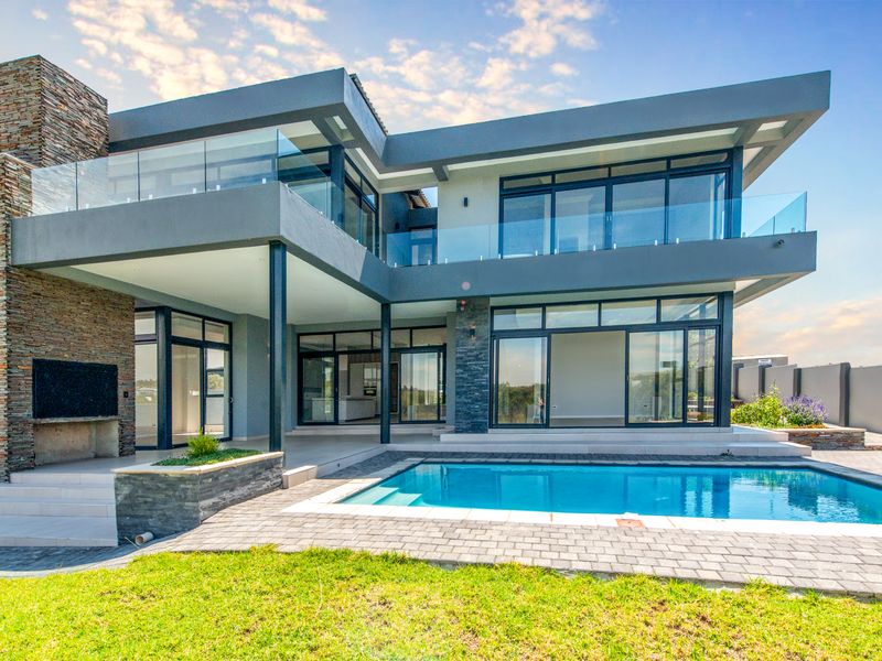Modern double-story residence featuring a swimming pool, expansive glass sliding doors, stone-clad fireplace, and spacious covered patio area.