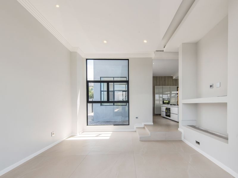 Modern open-plan living area featuring large format floor tiles, recessed lighting, a built-in fireplace, and a seamless transition to a contemporary kitchen.