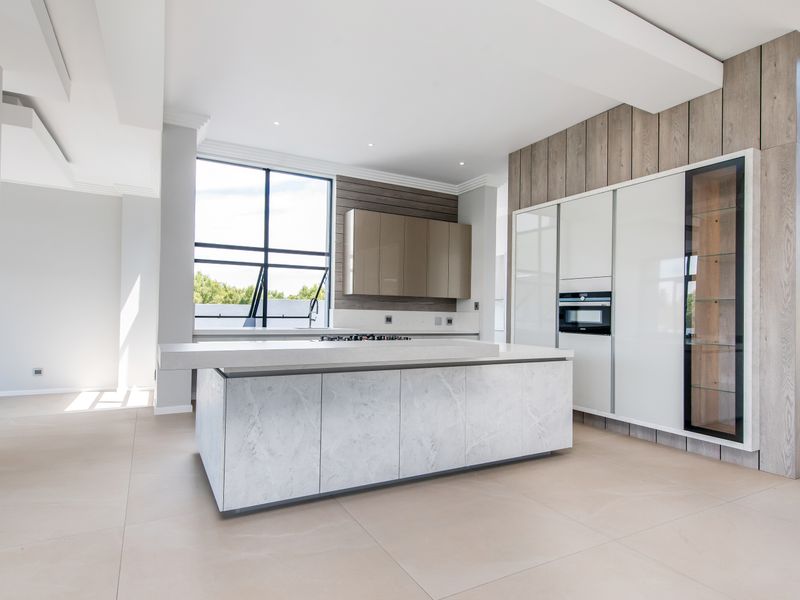Modern, high-end kitchen featuring a large marble-topped island, integrated cabinetry, built-in oven, and sleek contemporary finishes in an open-plan layout.