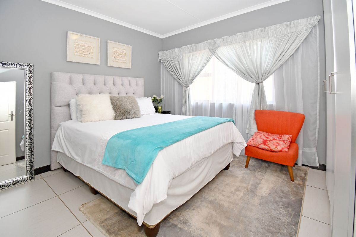 A well-maintained bedroom featuring neutral grey walls, tiled flooring, and a built-in wardrobe, offering a clean and comfortable living space.