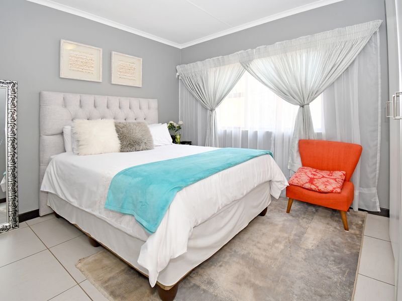 A well-maintained bedroom featuring neutral grey walls, tiled flooring, and a built-in wardrobe, offering a clean and comfortable living space.