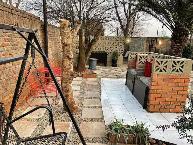 Outdoor entertainment area featuring a built-in brick braai, paved patio space, and decorative breeze block walling within a private garden setting.