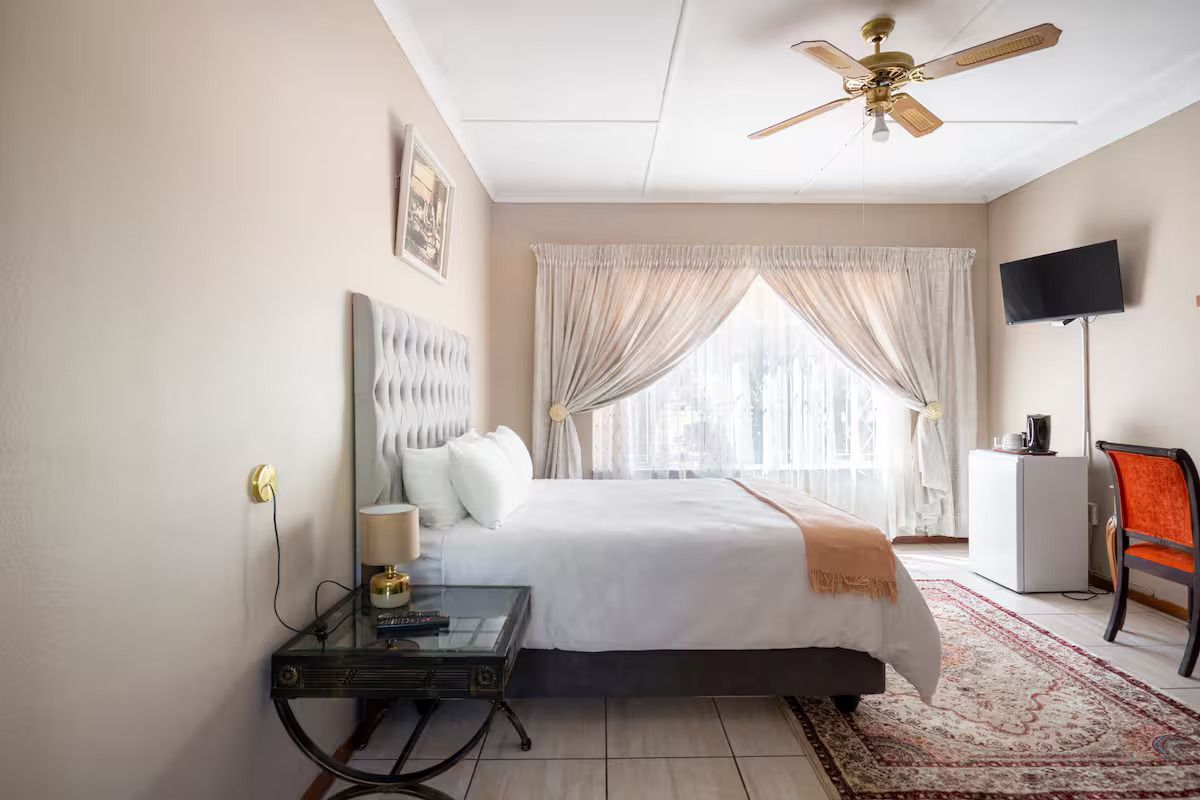 A well-maintained bedroom featuring tiled flooring and a ceiling fan, offering a comfortable and functional living space.