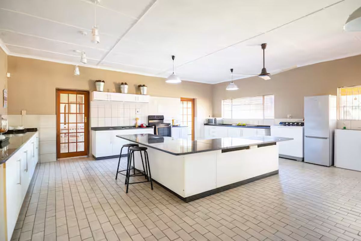 Spacious kitchen featuring a large central island, ample built-in cabinetry, tiled flooring, and a functional layout with integrated appliances.