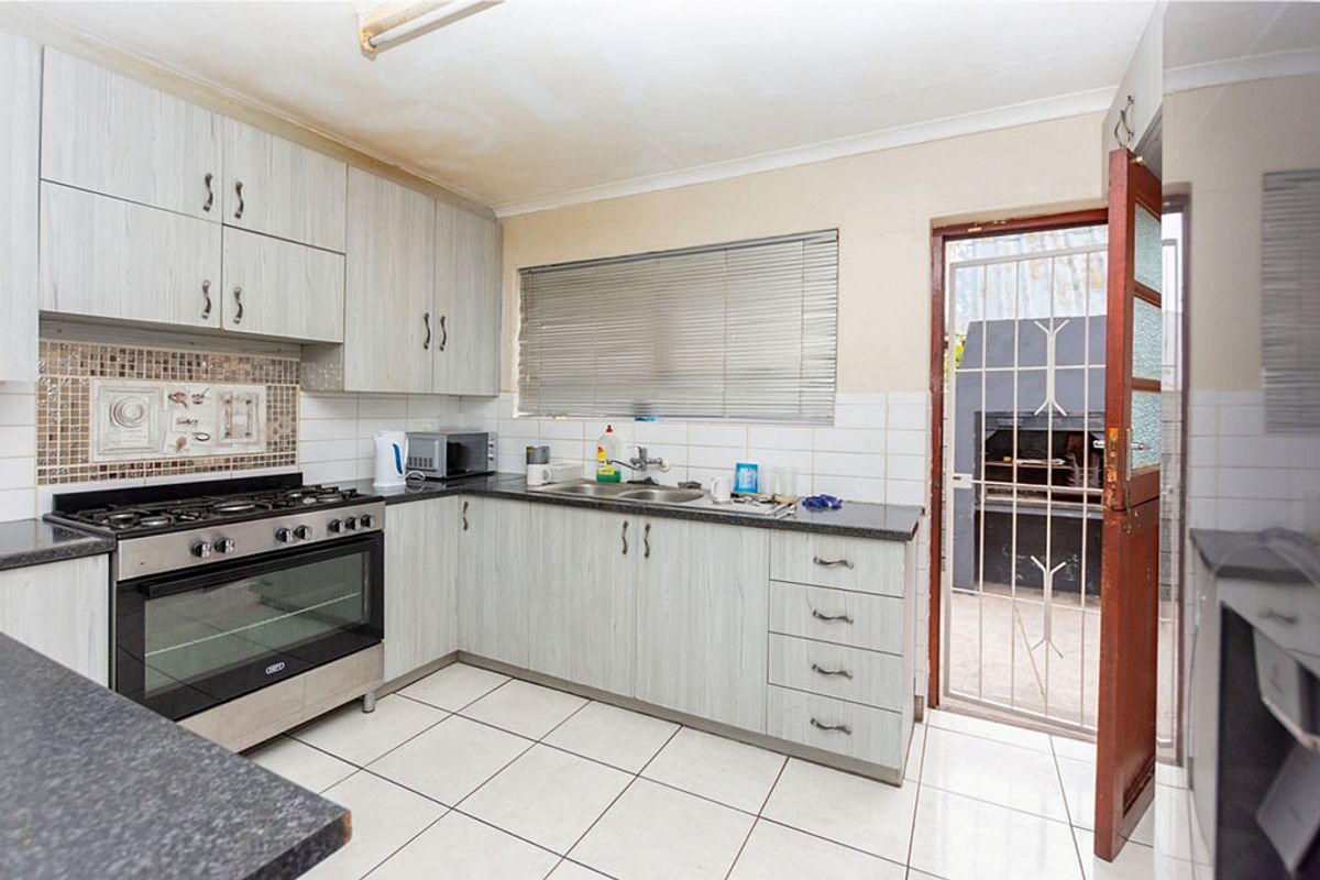 Functional kitchen featuring built-in cabinetry, gas stove, oven, and direct access to an outdoor patio area with a built-in braai.