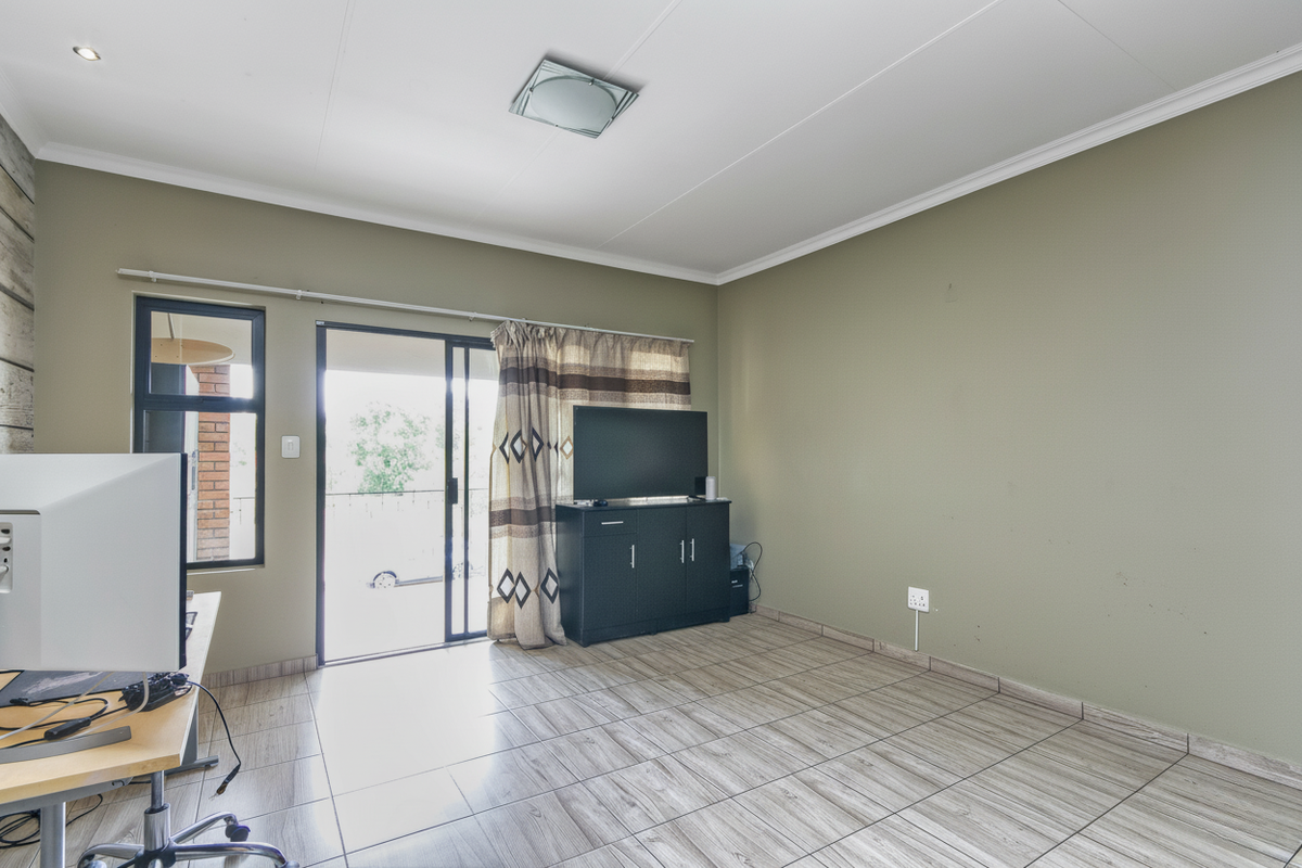 A spacious living room featuring tiled flooring, recessed ceiling lighting, and sliding glass doors providing access to an outdoor balcony area.