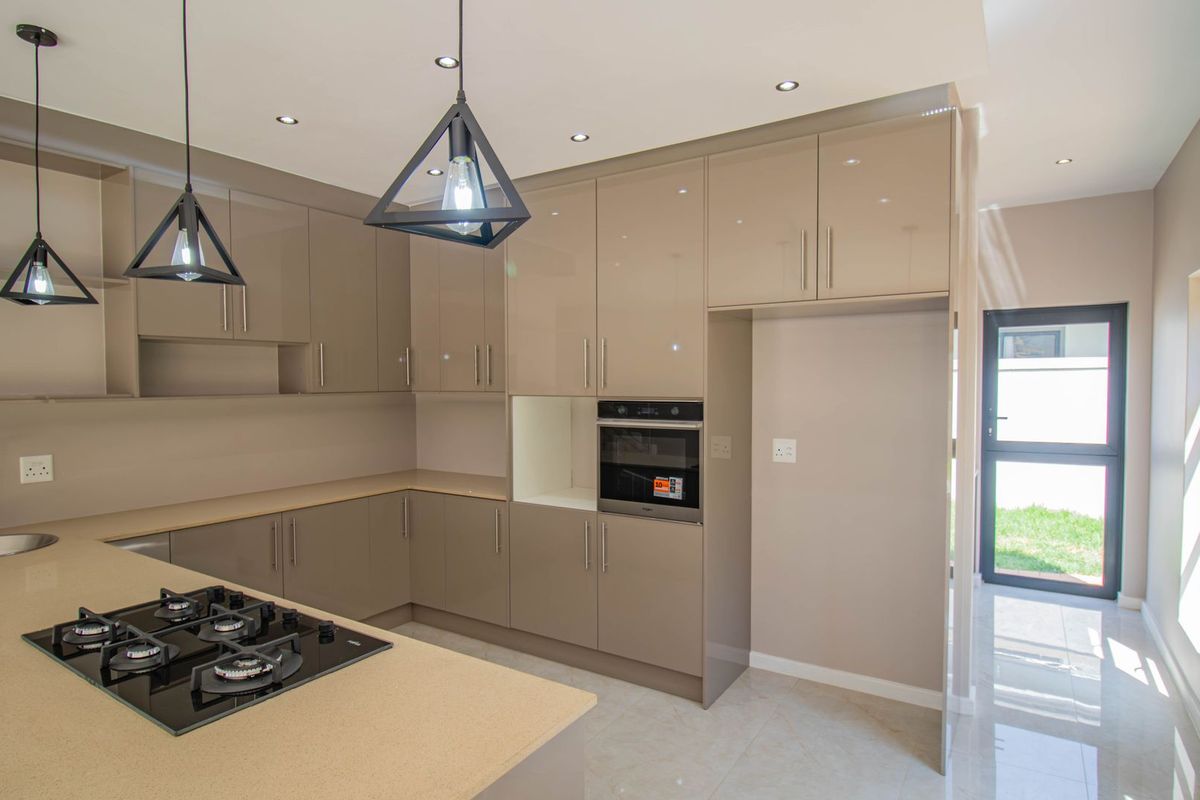 Modern kitchen featuring high-gloss cabinetry, stone countertops, a built-in gas hob, and an integrated oven, finished with sleek tiled flooring and recessed lighting.