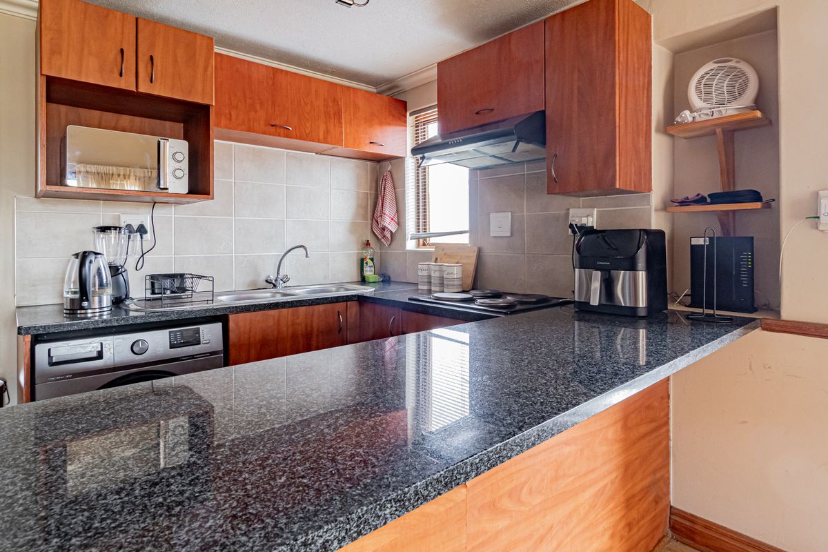 A functional kitchen featuring wooden cabinetry, granite countertops, a tiled backsplash, and integrated appliances, offering a practical layout for daily meal preparation.