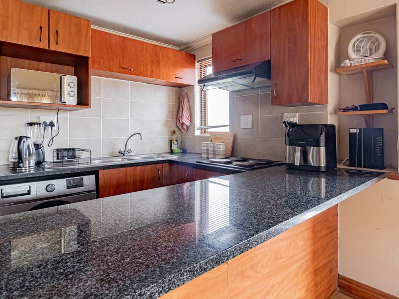 A functional kitchen featuring wooden cabinetry, granite countertops, a tiled backsplash, and integrated appliances, offering a practical layout for daily meal preparation.