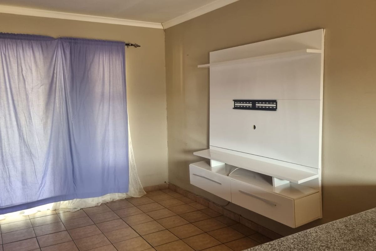 A living area featuring tiled flooring and a modern white built-in media unit, providing a clean and functional space for entertainment.